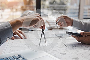 Architect working on blueprint in workplace with partnership and drawing compass