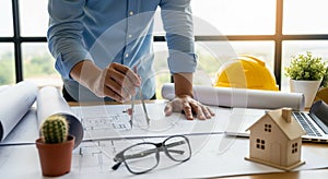 Architect working on blueprints with tools and model house