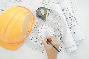 Architect working on construction blueprint. Architects workplace - architectural project, blueprints, helmet, measuring tape