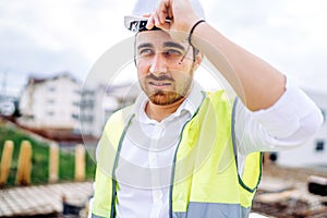 architect working on construction site, wearing hard hat and safety vest