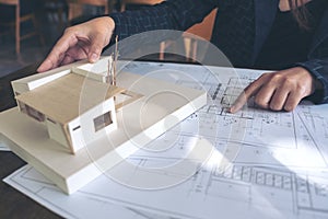 An architect working and pointing at architecture model with shop drawing paper