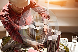 Architect working with a ruler, examining model in the office