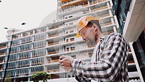Architect working with smartphone on construction site. Engineer check construction plan on smartphone. Construction Inspector
