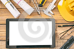 Architect workplace. Tablet with white blank screen, project construction blueprints and engineering tools on wooden desk, copy sp