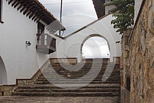 Architectonical details of Guatavita, colombian town. A white stone arc with stone floor a balcony and ceramic wooden roof