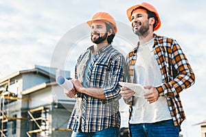 architects with blueprint and tablet looking away