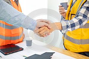 Architects and construction engineering handshake after meeting discuss structural blueprints calculate project completion.