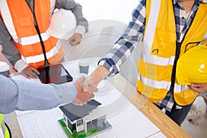 Architects and construction engineering handshake after meeting discuss structural blueprints calculate project completion.