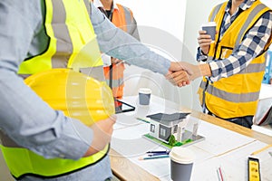 Architects and construction engineering handshake after meeting discuss structural blueprints calculate project completion.