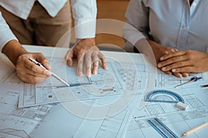Architects engineer working with blueprints on table and discussing project together at the meeting in the office