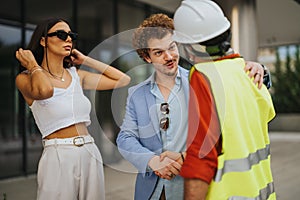 Architects and engineers discuss blueprint details for a sustainable building project at a city construction site.