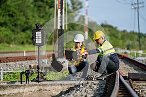Architects and engineers sit and use laptops to point out railroad tracks where repairs to the railroad switch construction