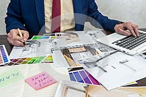 Architects hands drawing of modern apartaments with colour sample and laptop on creative desk, office. Man choosing colors for