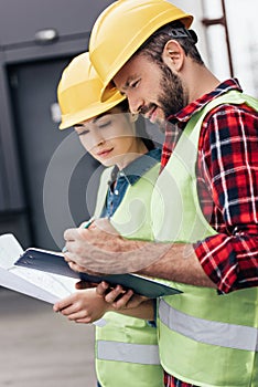 architects in helmets working with blueprint and clipboard