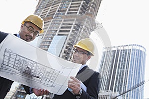 Architects looking at blueprint on construction site, Beijing
