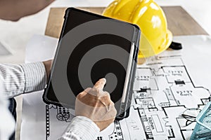 Architects are looking at blueprints designed on tablets, designing the house according to the homeowner`s needs. photo