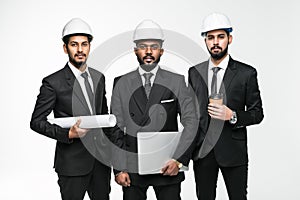 Architects next project. Three indian businessmen architect in the construction helmets standing isolated on white background