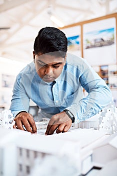 Architects think with their hands. a young architect designing a building model in a modern office.