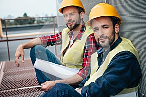 architects working with blueprint sitting on construction