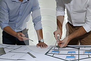 Architects working with construction drawings at table in office, closeup