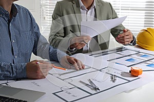 Architects working with construction drawings at table in office, closeup