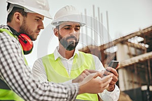 Architects working with smartphone on construction site