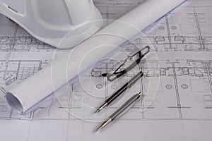 Architects workplace - architectural blueprints with measuring tape, safety helmet, glasses and propelling pencil on table. Top vi