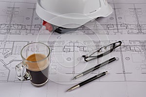 Architects workplace - architectural blueprints with safety helmet, glasses, coffee and propelling pencil on table. Top view.