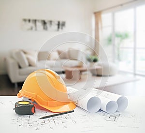 Architectural blueprint with safety helmet and tools over modern living room interior