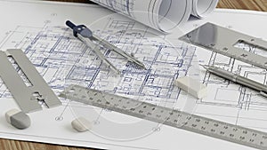 Architectural blueprints with drafting tools on a wooden table