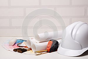 Architectural blueprints, hard hat, color palette guide, tools on light background. Concept of construction or design office