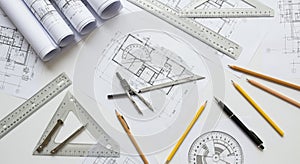 Architectural blueprints are spread on a table alongside drafting