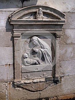 Architectural detail - a bas-relief sculpture of the Virgin Mary with the baby Jesus. Venice, Italy. The bas-relief is