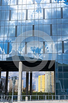 Architectural detail of the facade with multiple reflections of cloudy sky and the sun