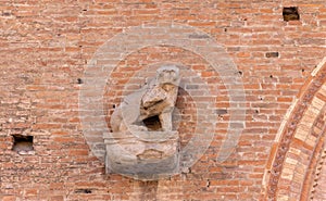 Architectural detail featuring a stone lion sculpture on a brick wall in Bologna