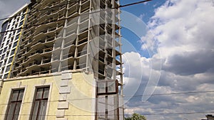 Architectural detail of high frame of monolithic concrete building under construction and old demolished house in front