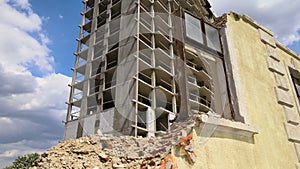 Architectural detail of high frame of monolithic concrete building under construction and old demolished house in front