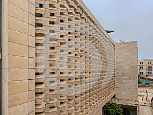 architectural facade with geometric stone patterns creating depth and shadow. Beige limestone blocks form a dynamic
