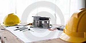architectural model of houses on desk with drawing technical tools safty helmet and blueprint rolls for building