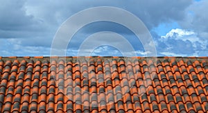 Architectural textured background of red brown ceramic tile against a blue sky.Roof of a house with modern shingles.
