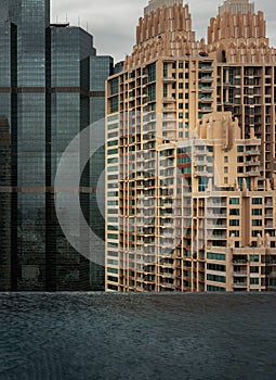 Architectural view of city skyscrapers. Two modern high-rise buildings with light reflection of Skylounge infinity pool