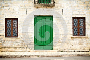 Architecture details from the Renaissance - green painted wooden door and two windows with a grate of a stone house in Kavarna