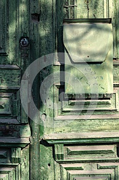 Architecture element. An old green wooden door with a mailbox.