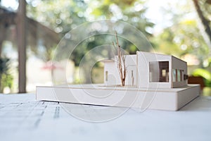 An architecture model with shop drawing paper and laptop on table in office with blur nature