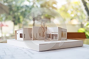 An architecture model with shop drawing paper and laptop on table in office with blur nature