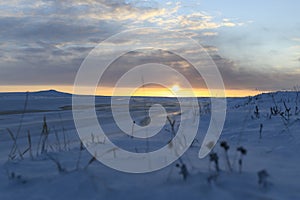 Arctic landscape in winter time. Small river with ice in tundra. Sunset