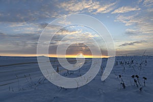 Arctic landscape in winter time. Small river with ice in tundra. Sunset