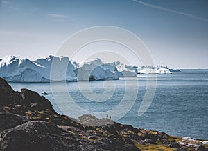 Arctic nature landscape with icebergs in Greenland icefjord with midnight sun sunset sunrise in the horizon. Early