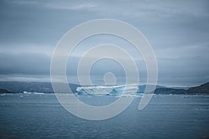 Arctic nature landscape with icebergs in Greenland icefjord with midnight sun sunset sunrise in the horizon. Early