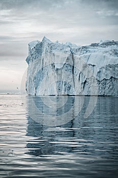 Arctic nature landscape with icebergs in Greenland icefjord with midnight sun sunset sunrise in the horizon. Early